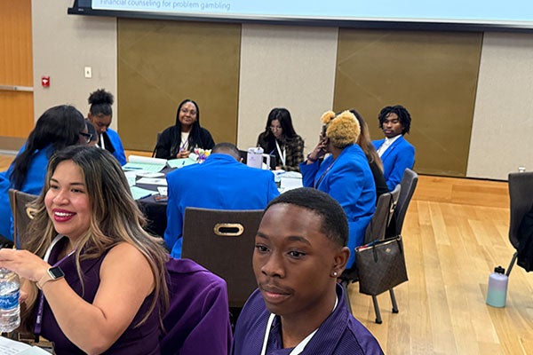 People sitting at round tables, smiling.